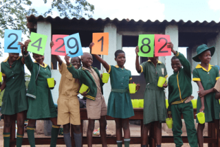 Children in Zimbabwe celebrating Mary's Meals now serving meals to more than 2.4 million children every school day.